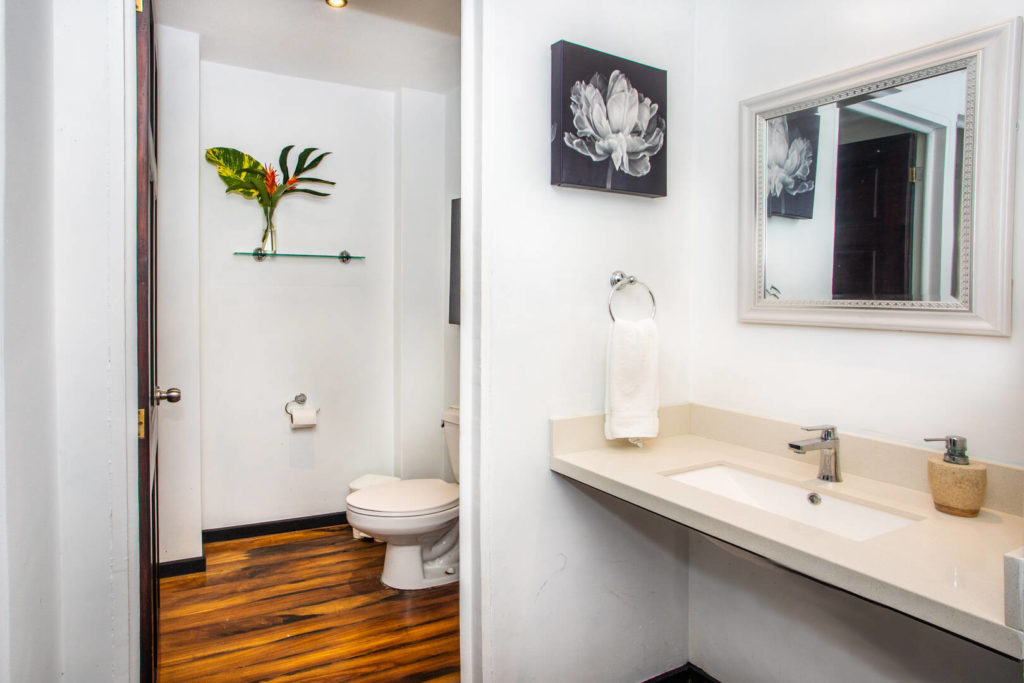 This luxurious bathroom is cleanly designed in white with a beautiful wooden floor.