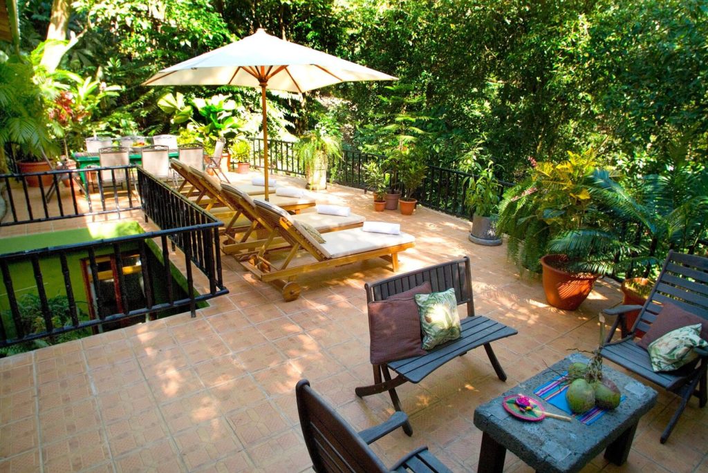 The huge terrace overlooks the main pool with seating and dining areas among tropical plants and decor.