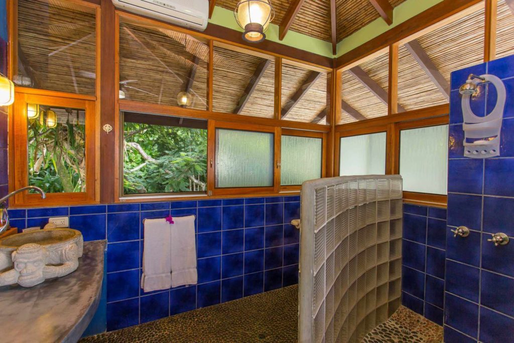 A mixture of tiles, stonework, wood, and bamboo in this bathroom creates a unique and pleasant design.