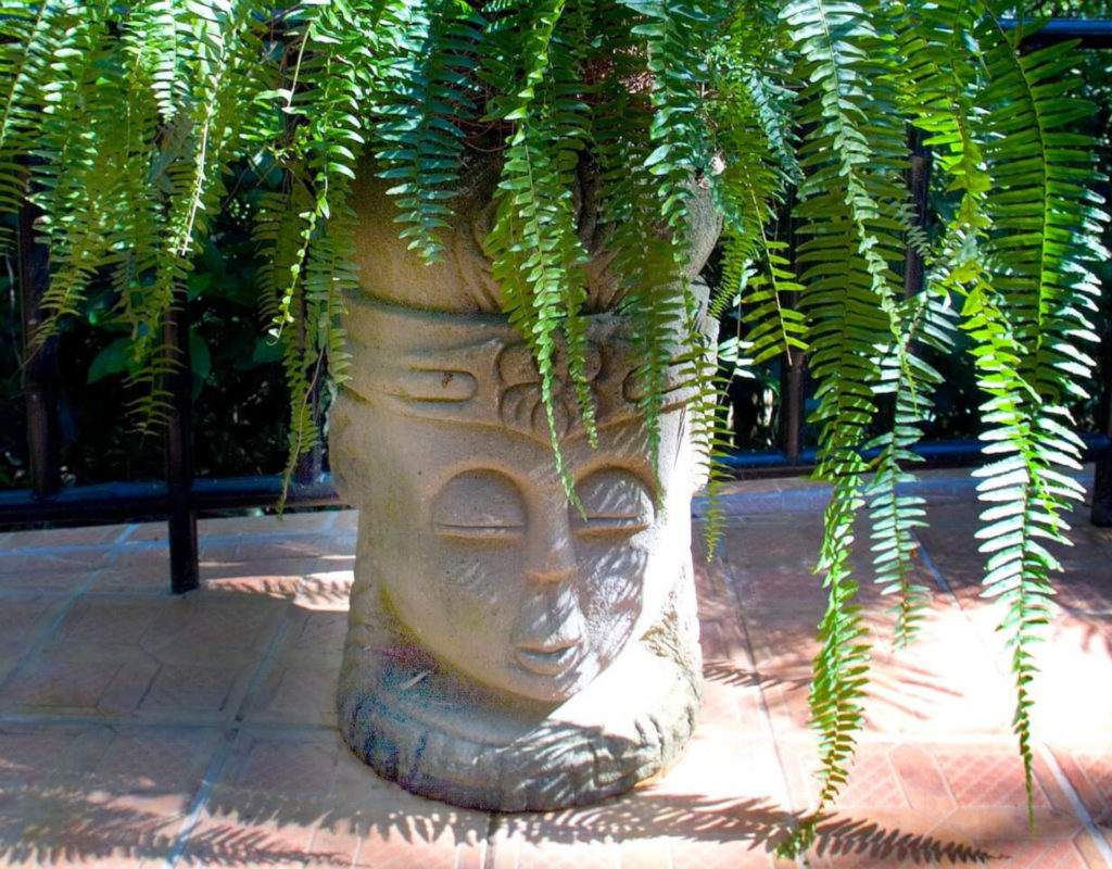 There are fun concrete statue-like planters around the garden filled with vibrant tropical plants.