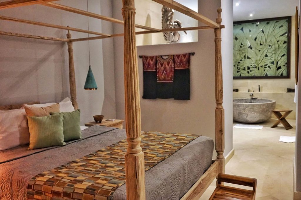 This luxury bedroom features a wooden poster king bed and a huge granite bathtub in the ensuite bathroom.