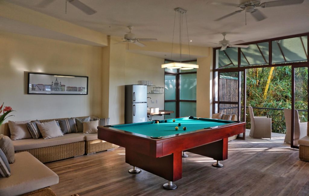 The games room has a wet bar, pool table, large-screen TV, refrigerator, and a comfortable sectional.