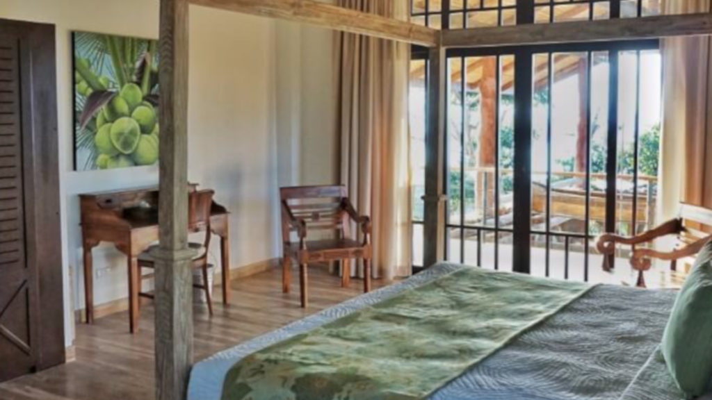 Gorgeous wooden furniture and tropical artwork adorn this bedroom with a private balcony.