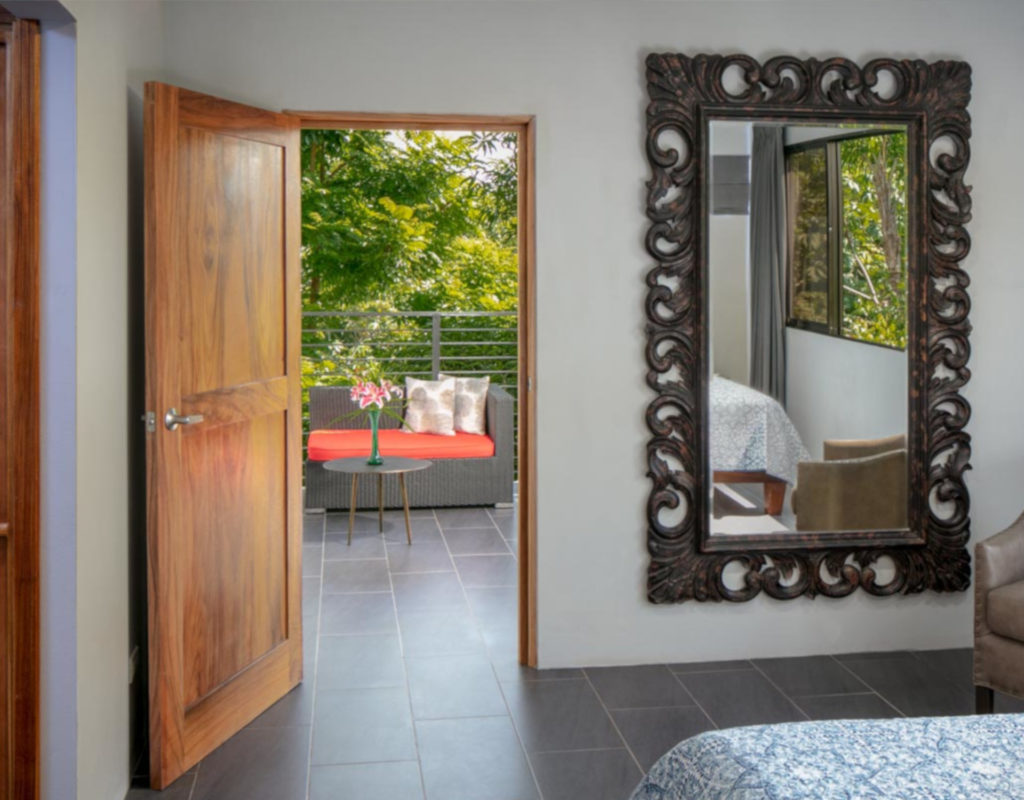 This bedroom features a tall beautifully designed mirror.