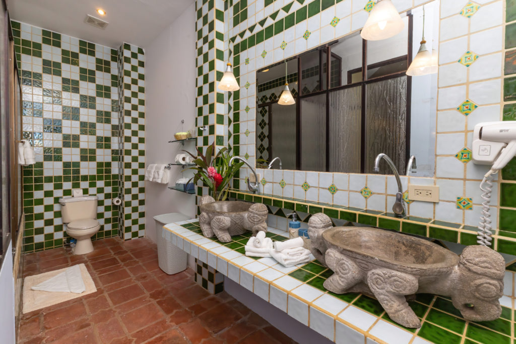 Uniquely designed bathroom with ceramic tiled countertops with hand-carved stoned lavatory.