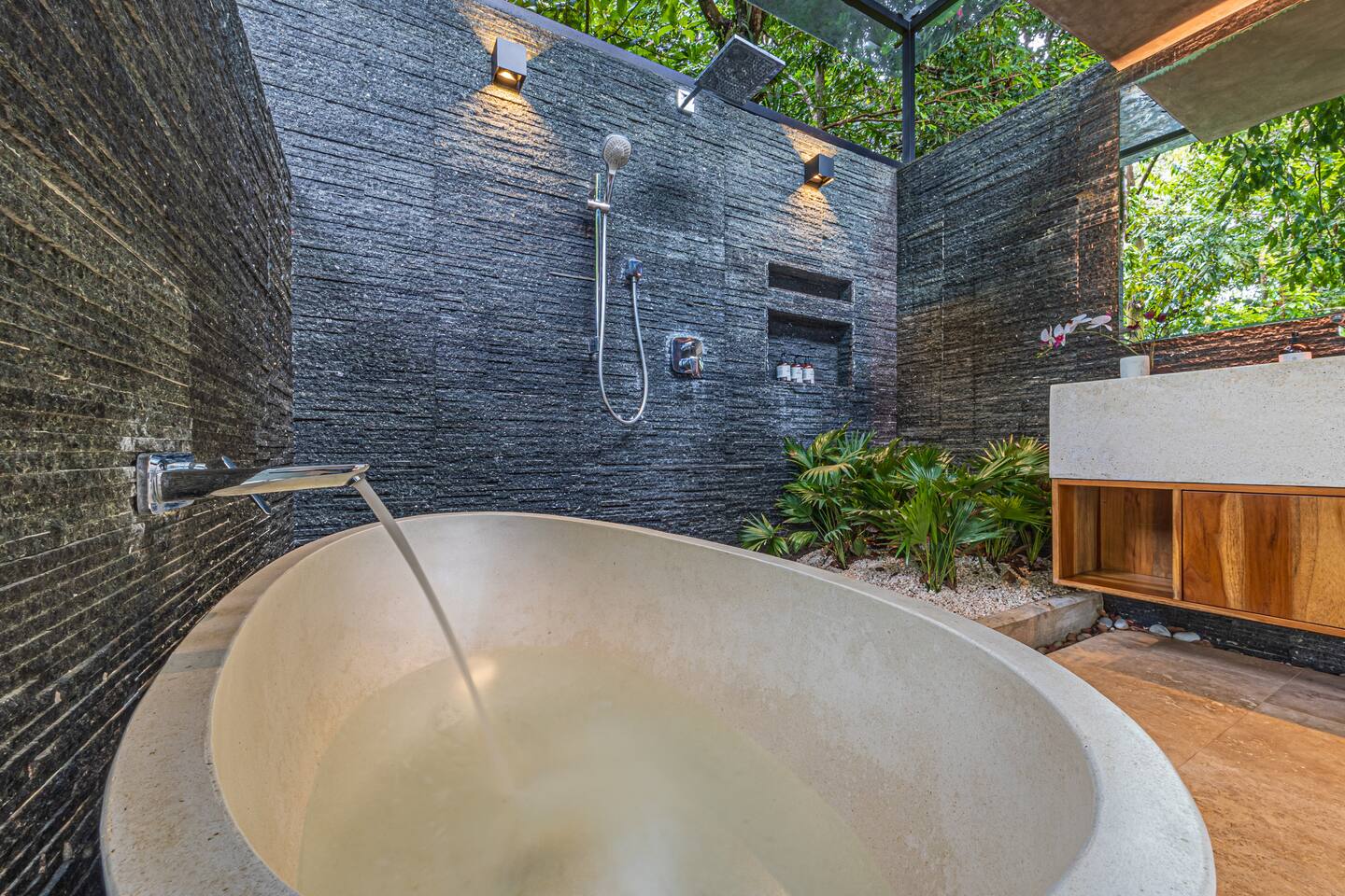 Stone soaking tub in an open-air bathroom surrounded by tropical plants near Dominical, Costa Rica.