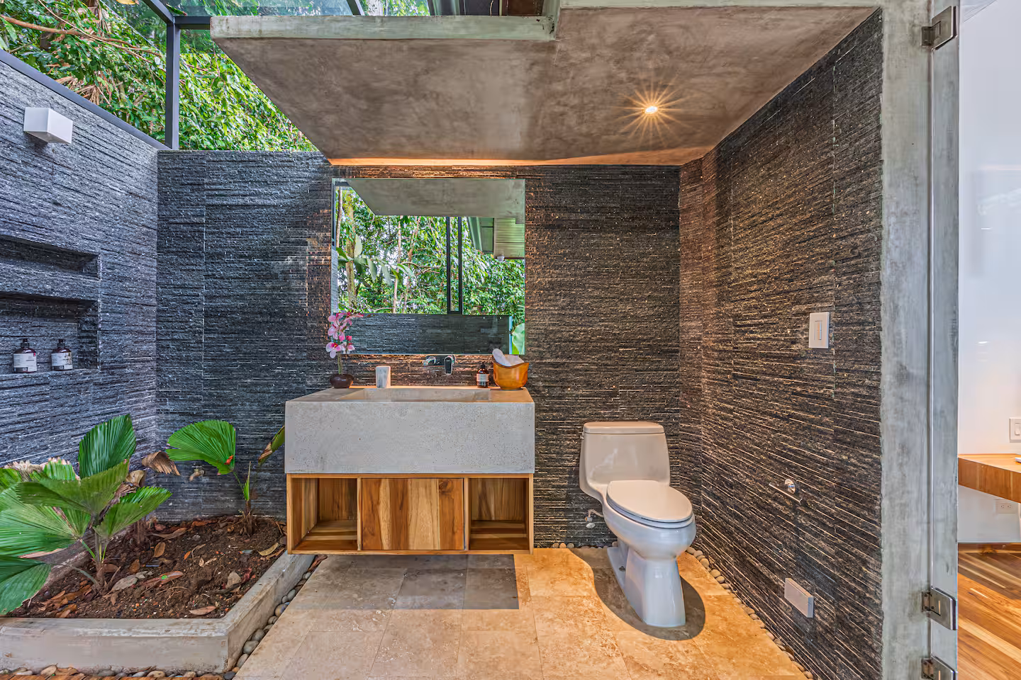 Bathroom with large windows and garden views surrounded by tropical greenery near Dominical, Costa Rica.