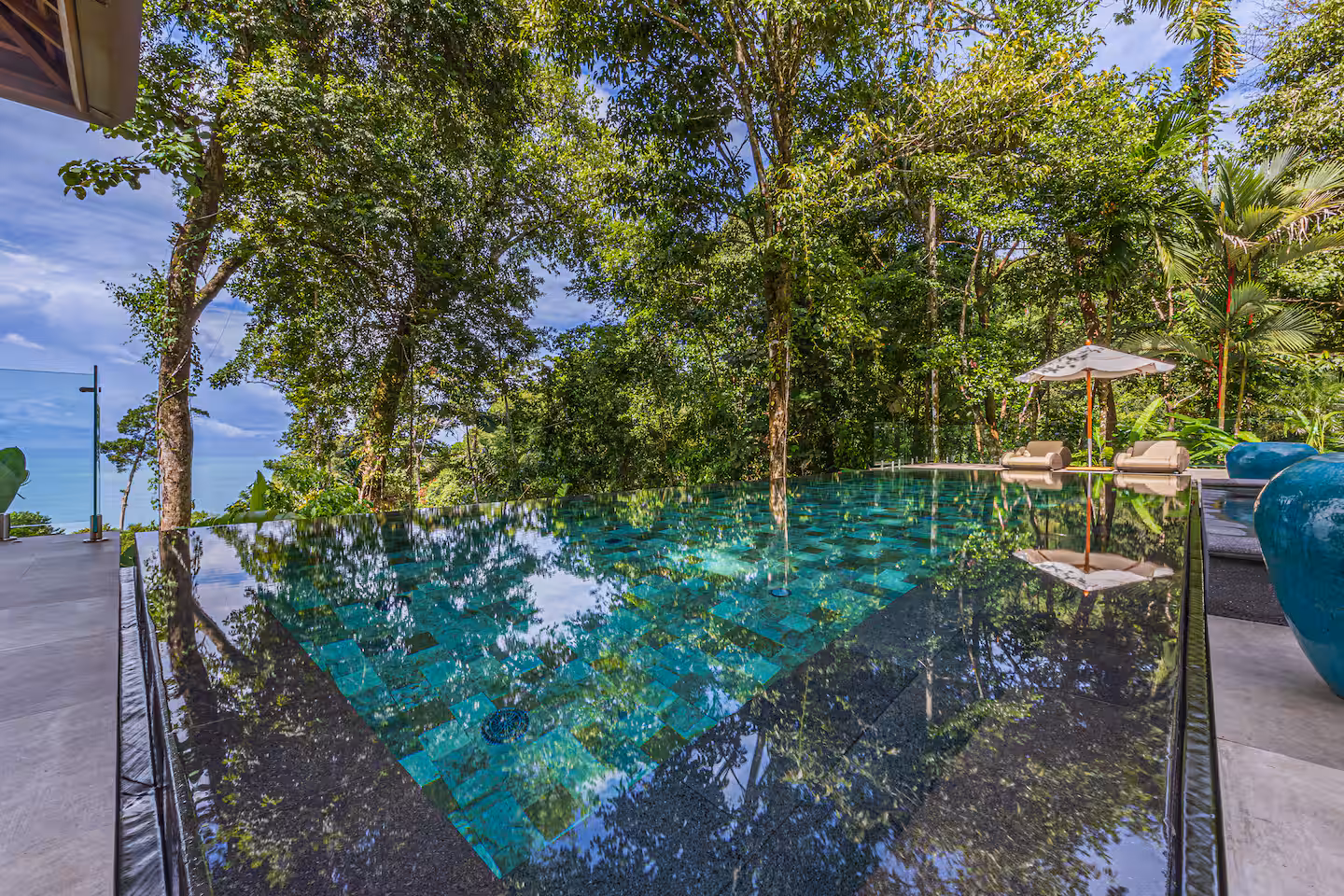 Infinity-edge pool reflecting tropical jungle greenery near Dominical, Costa Rica.