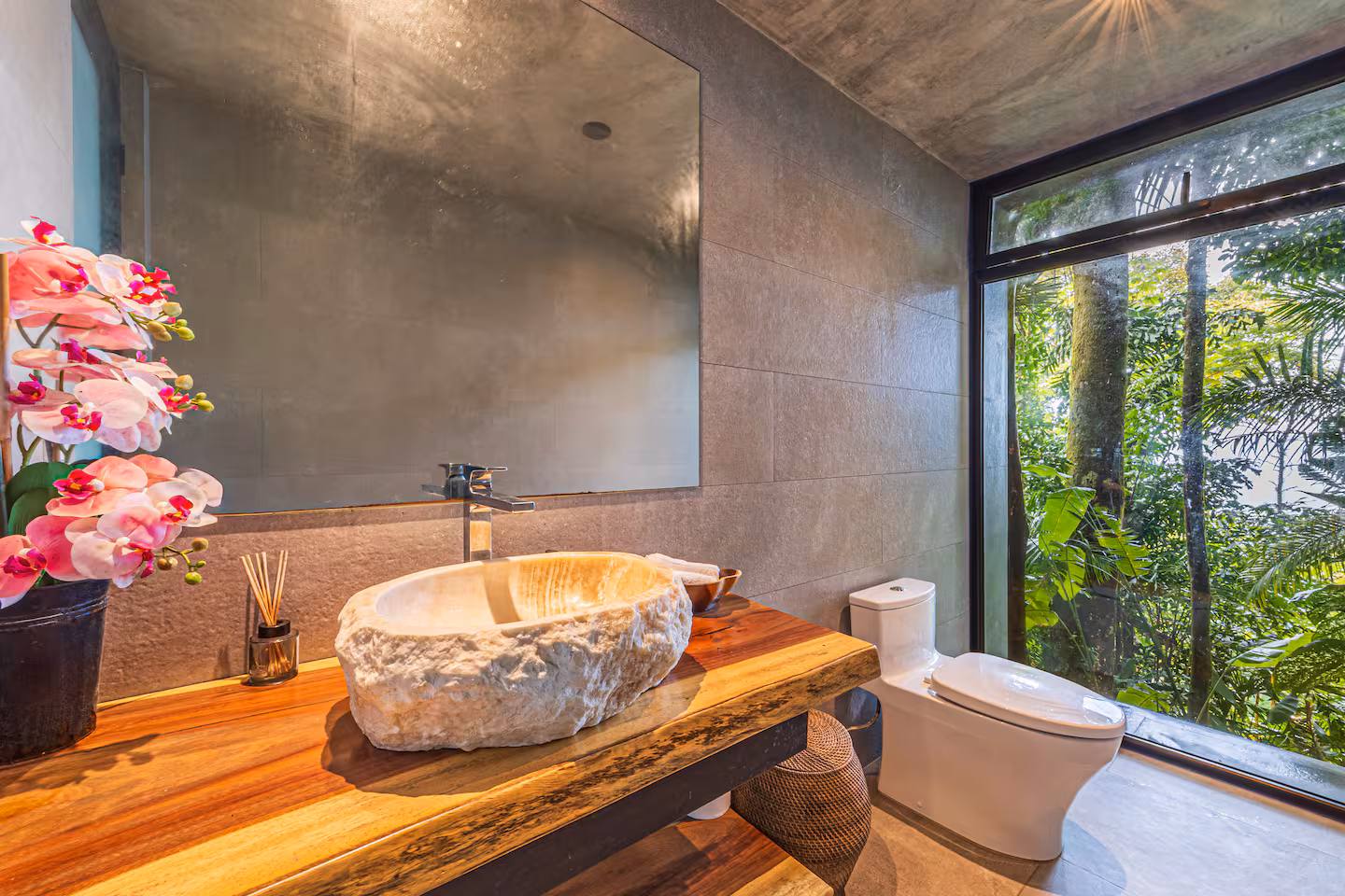 Bathroom with natural stone finishes and large window overlooking tropical jungle near Dominical, Costa Rica.