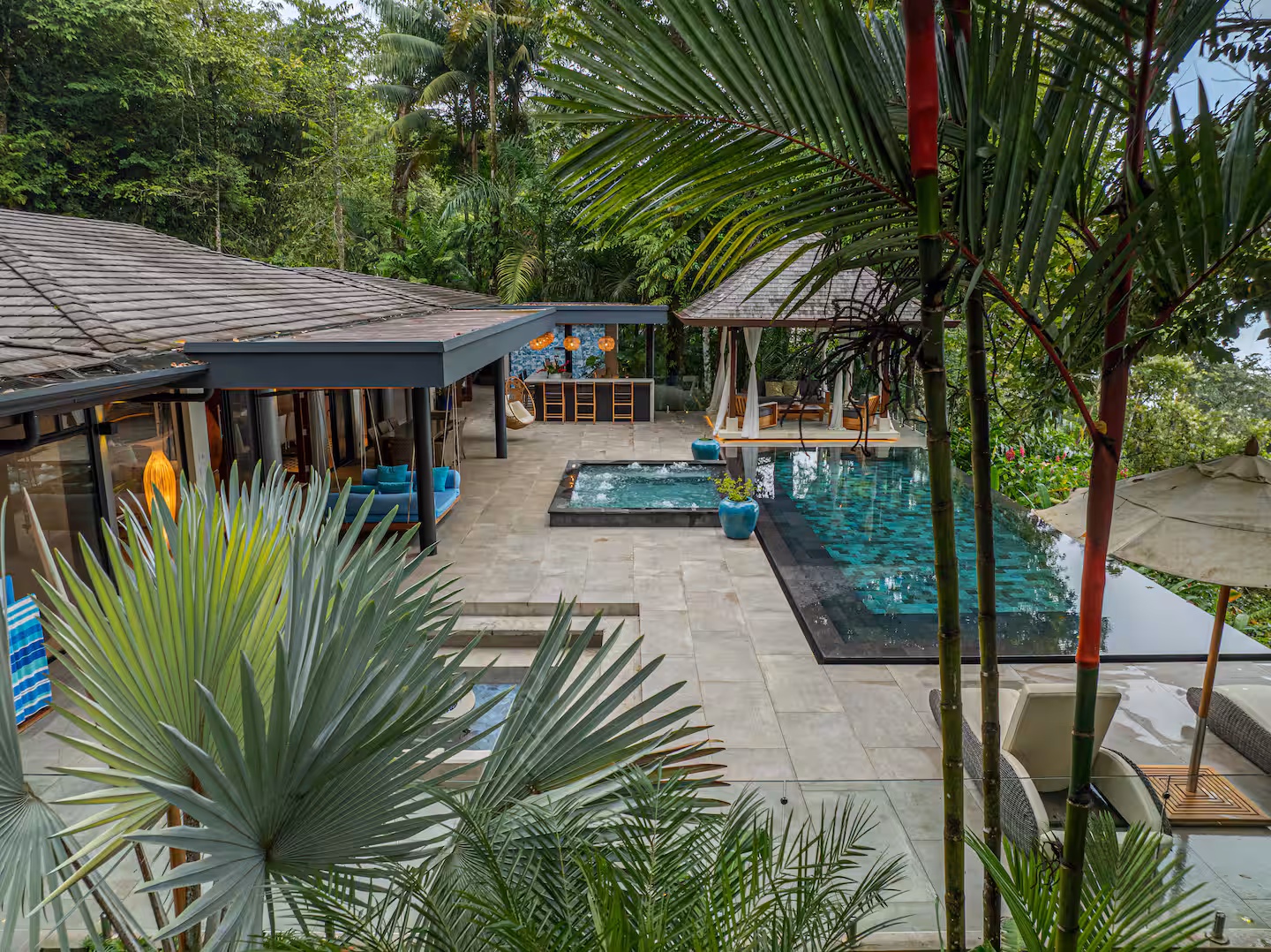 Open-air living areas and pool terrace surrounded by tropical rainforest near Dominical, Costa Rica.