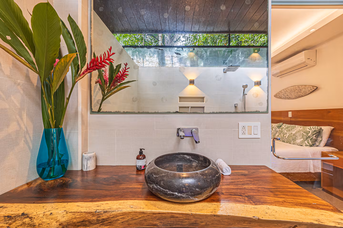 Bathroom connected to bedroom with stone vessel sink, wood vanity, and jungle greenery near Dominical, Costa Rica.