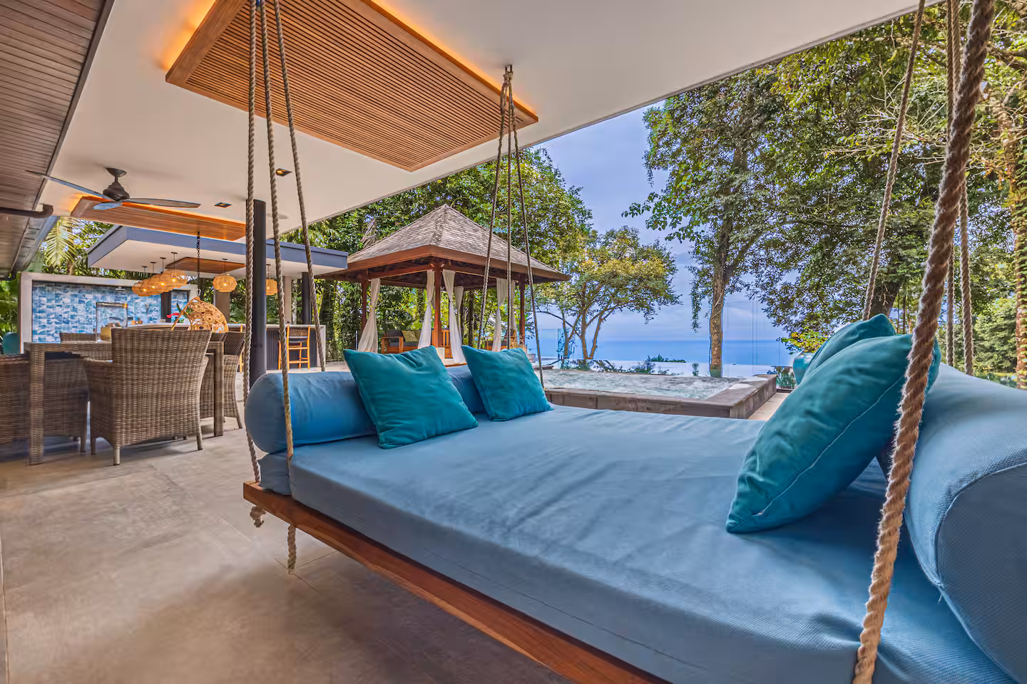 Suspended outdoor lounger overlooking infinity pool, jungle, and distant Pacific Ocean near Dominical, Costa Rica.