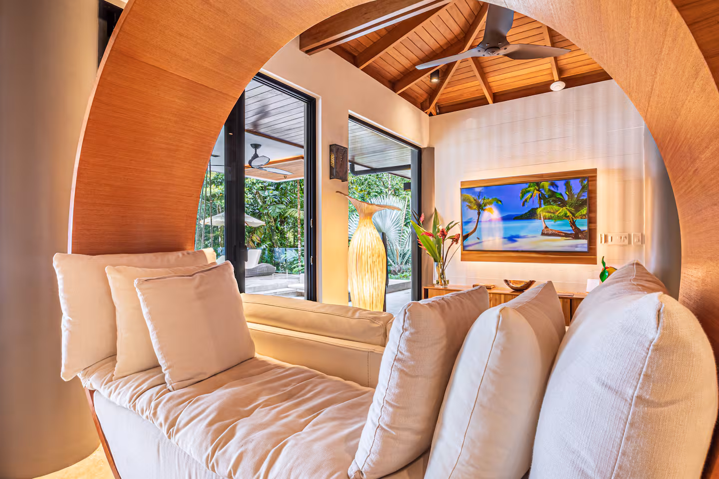 Indoor lounge with wood detailing and large glass doors opening to jungle near Dominical, Costa Rica.