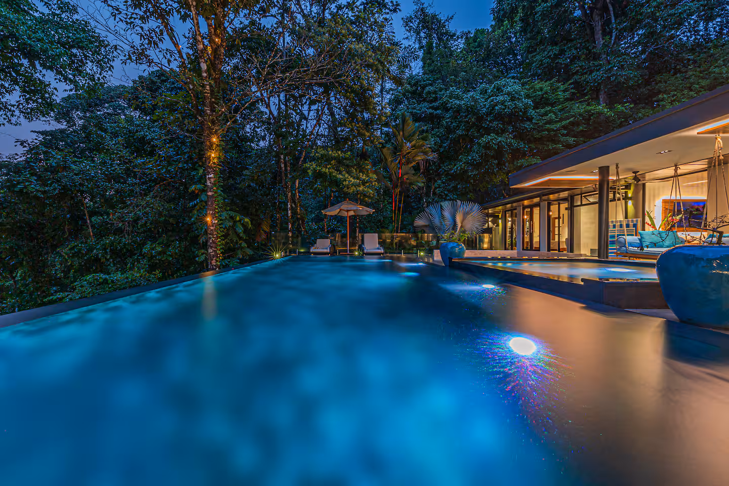 Infinity-edge pool illuminated at night with jungle surroundings near Dominical, Costa Rica.