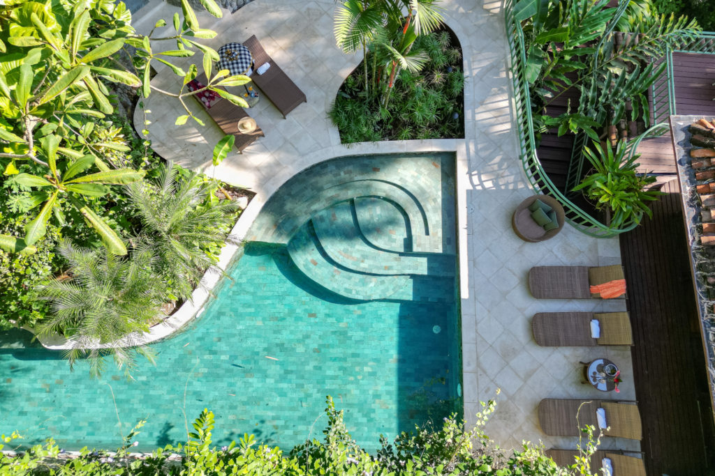 A recently renovated pool space and lounge area surrounded by lush tropical gardens.