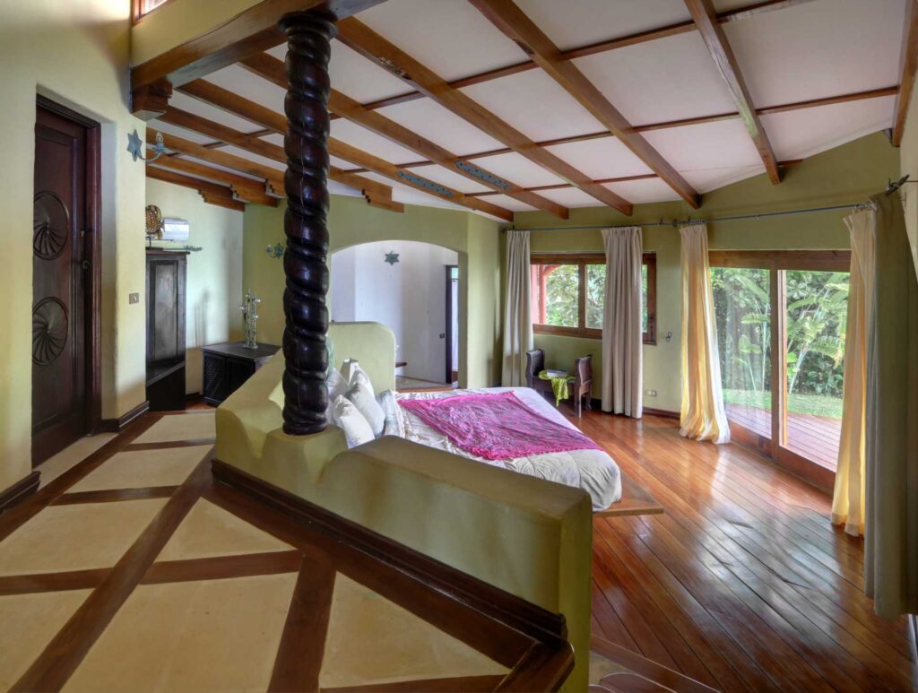 A grand master suite with warm wood, natural light, and garden views.