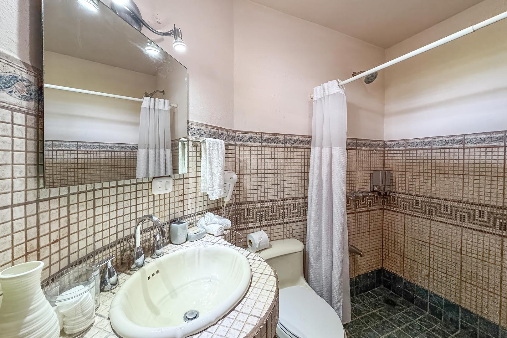 Ensuite bathroom with tiled shower, sink vanity, mirror, and toilet