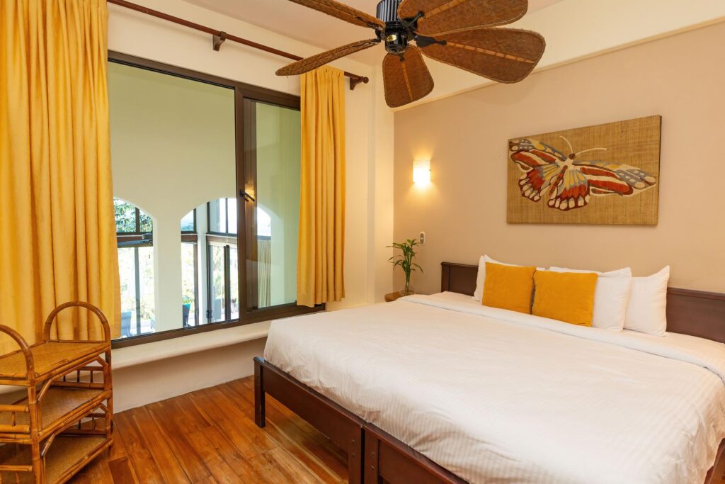 A cozy bedroom filled with warm tones and natural light, offering a calm, comfortable space to unwind after a day exploring the surrounding rainforest.