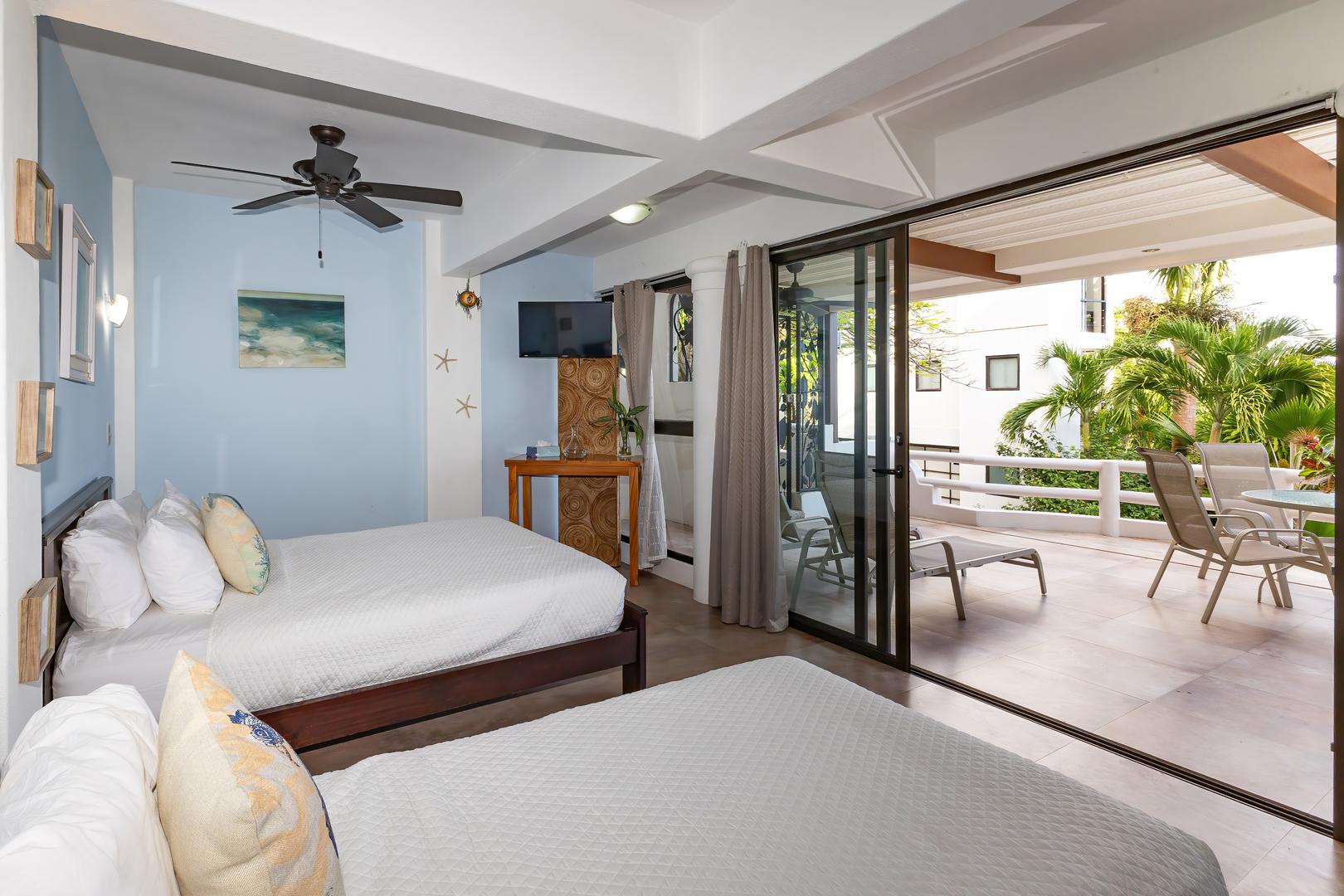 Twin bedroom with two beds opening onto a private terrace with outdoor seating