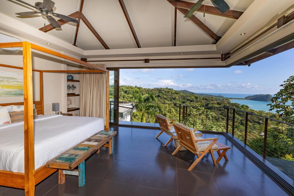 Bedroom with open terrace, seating area, jungle landscape, and panoramic ocean view in Manuel Antonio