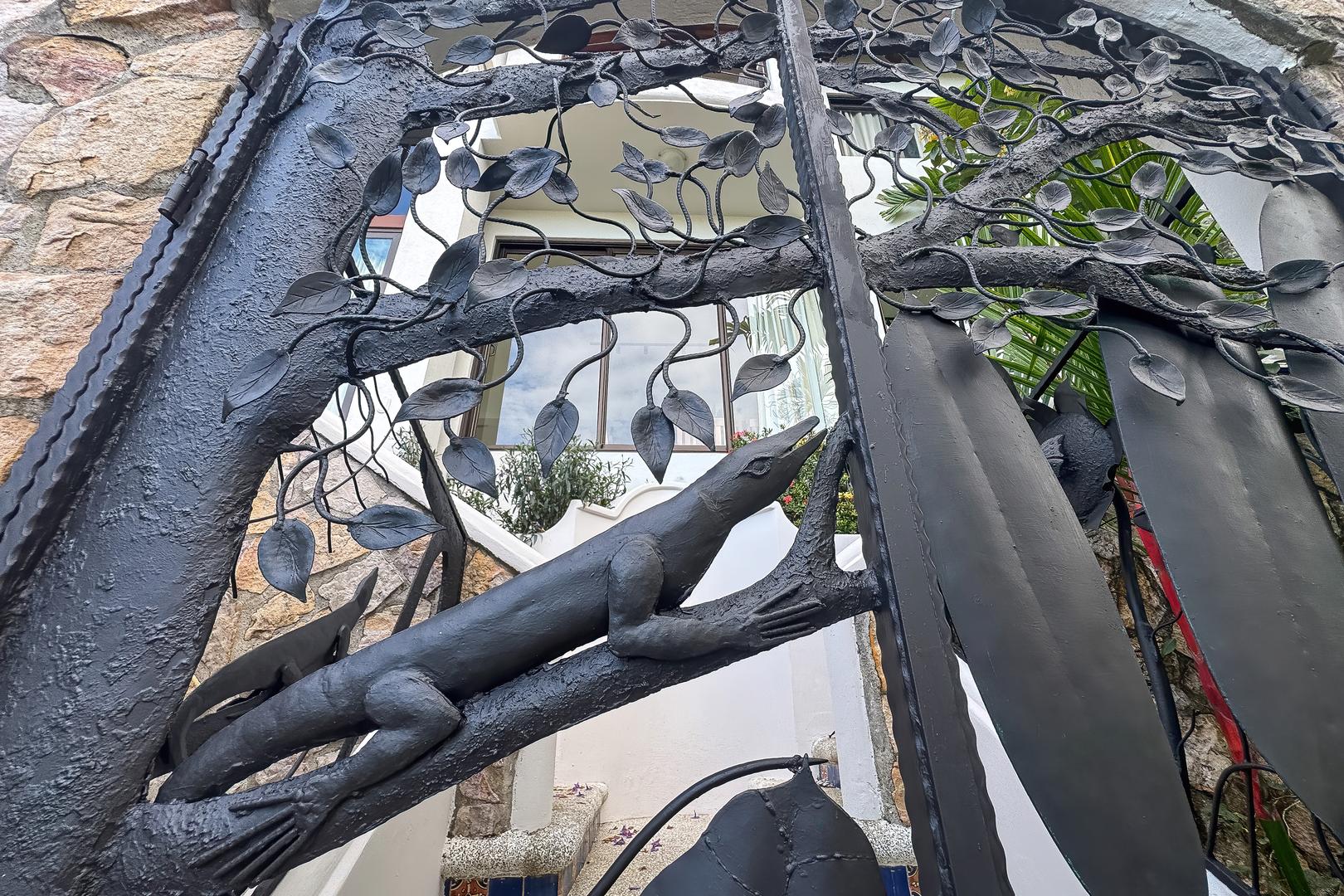 Custom iron front gate with sculpted lizard and vine details at the villa entrance