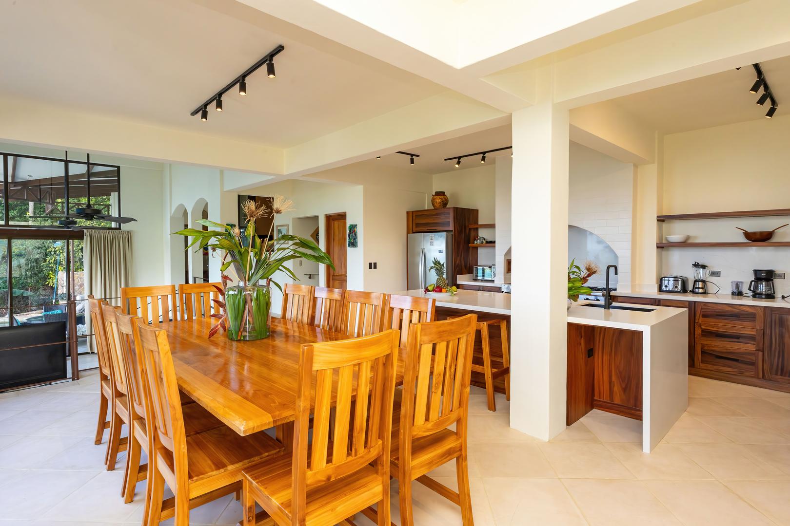 Open kitchen and dining area with wooden dining table, island seating, and modern appliances