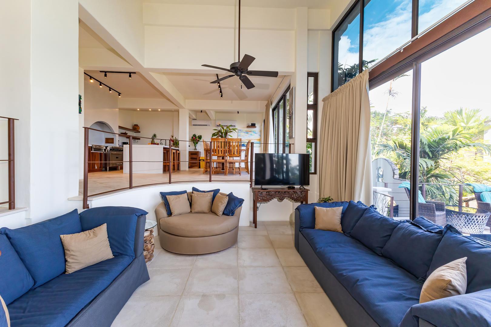 Sunken living room with sofas, open layout, large windows, and tropical views