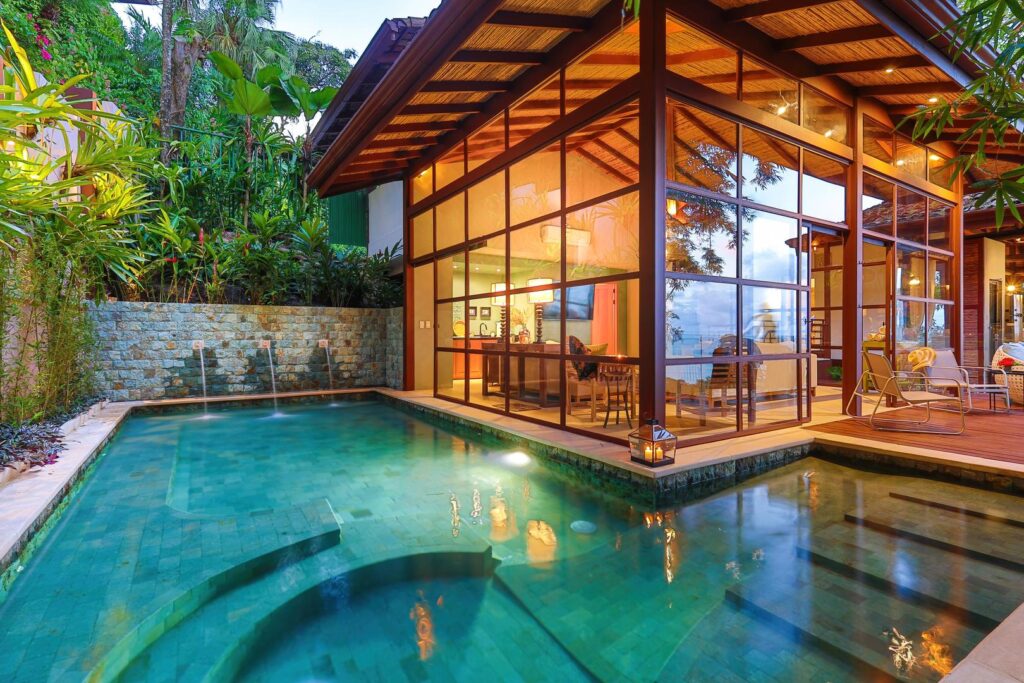 The additional pool reflects warm light and natural textures, creating a peaceful retreat immersed in bamboo and tropical calm.