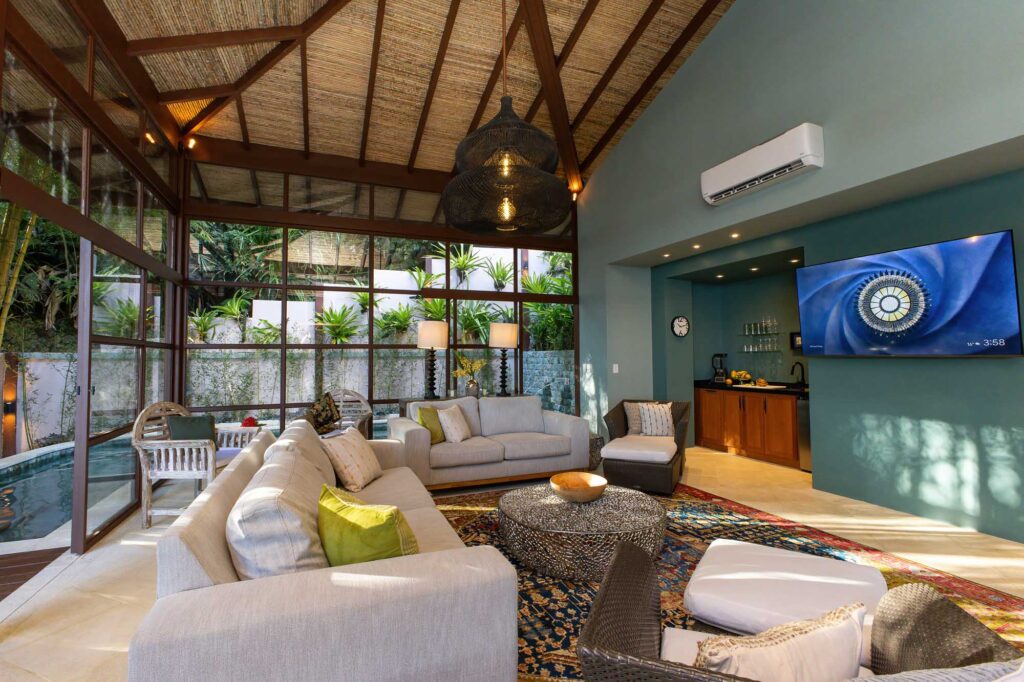 The open-plan lounge of the new wing blends vaulted ceilings, woven textures, and soft seating into a relaxed space designed for gathering, unwinding, and enjoying the surrounding jungle.