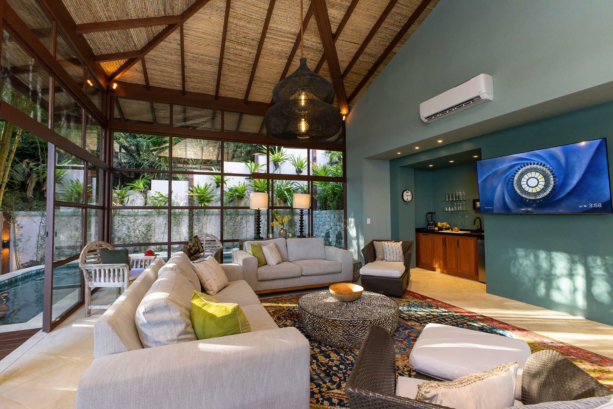 Open-plan interior lounge of the new wing with vaulted wood ceiling, seating area, woven pendant light, and glass walls at a luxury villa in Manuel Antonio, Costa Rica.
