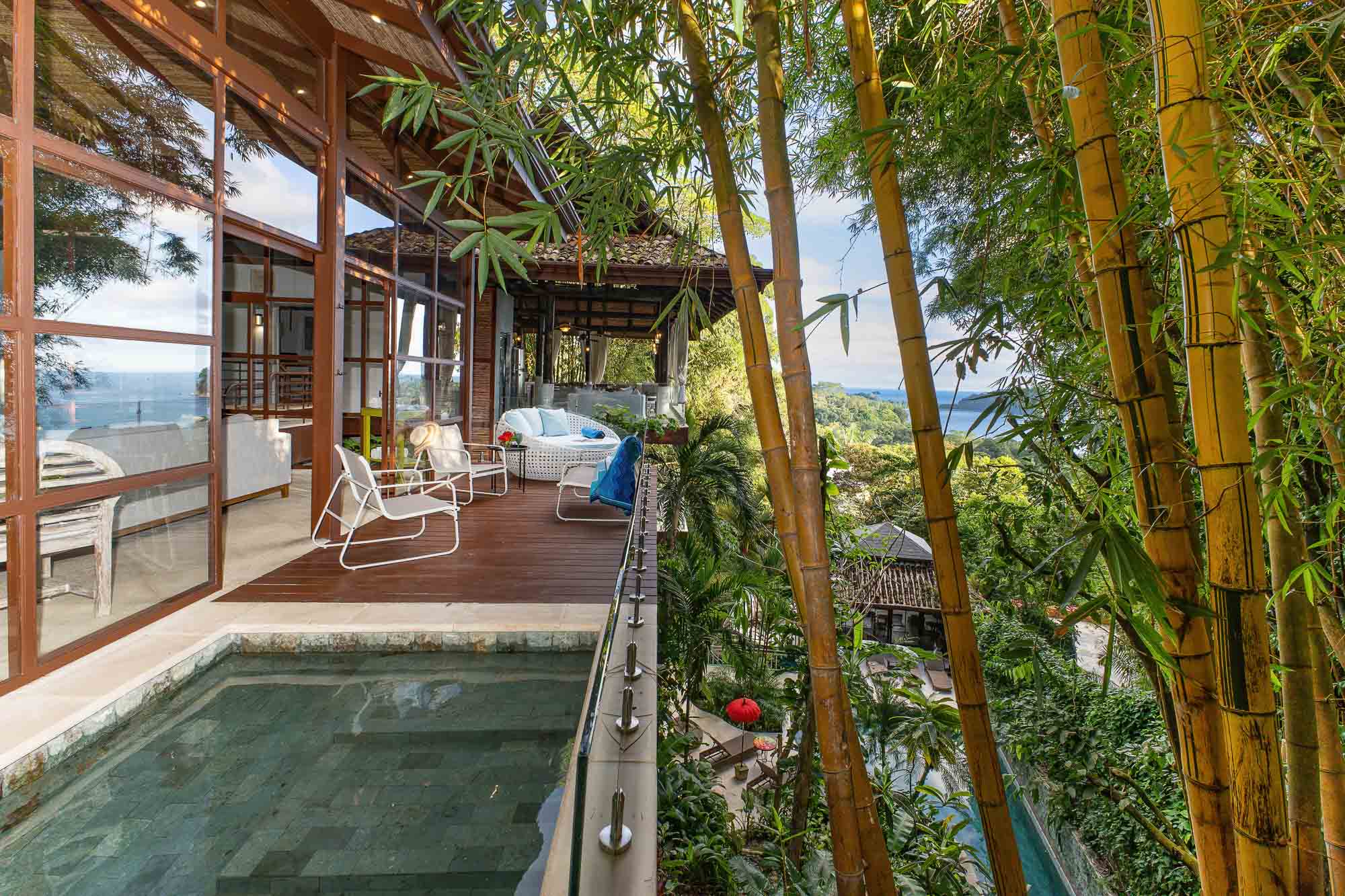 Wooden deck beside the new wing with outdoor seating, bamboo grove, glass railing, and jungle views at a luxury villa in Manuel Antonio, Costa Rica.
