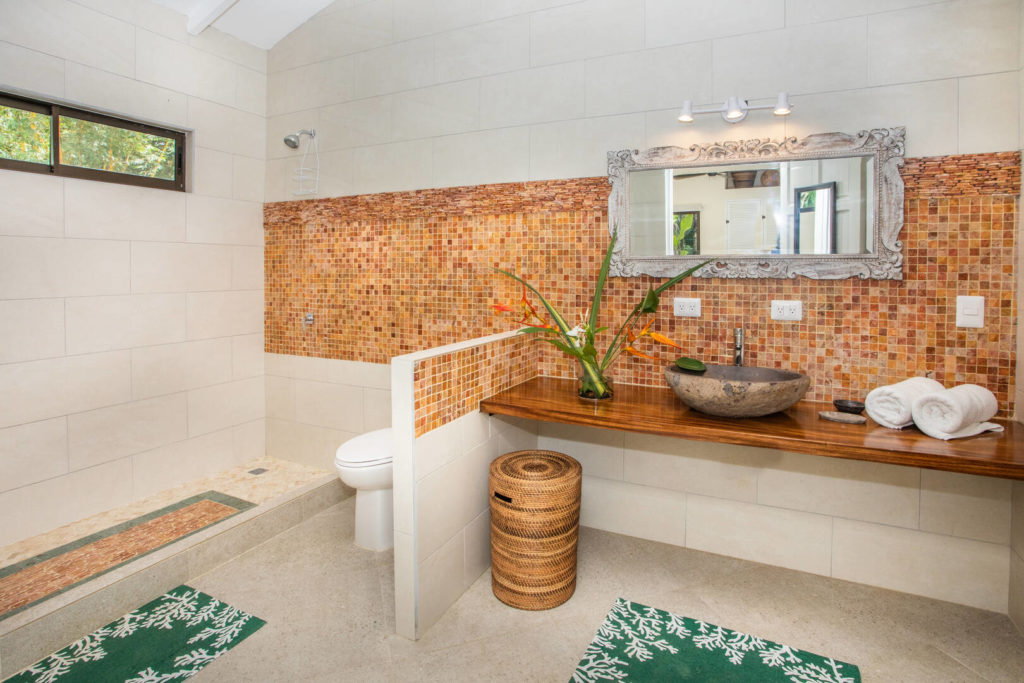 Each bathroom has a unique style. This one has beautiful tile work, a stone sink, and a native wood counter.