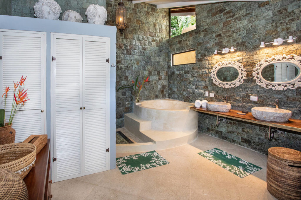 This opulent master ensuite has some stunning handcrafted features, his and hers stone sinks, and a huge bathtub.