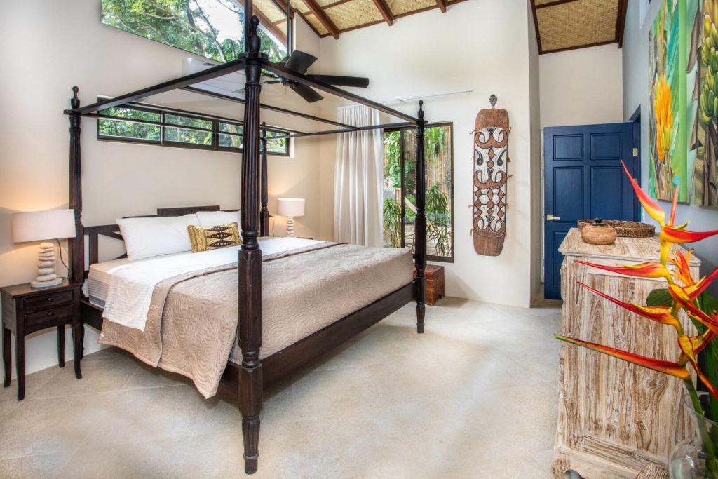 This light and airy master bedroom has a stunning dark wood king poster bed.