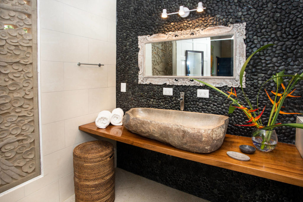 This bathroom features an amazing wall of black stones and other natural handcrafted details.