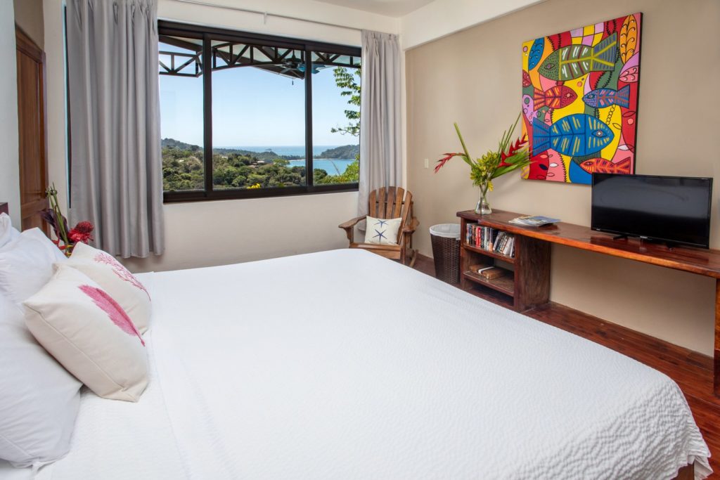 The spacious master bedroom on the main level features a comfy king bed, ensuite bathroom, and ocean view.